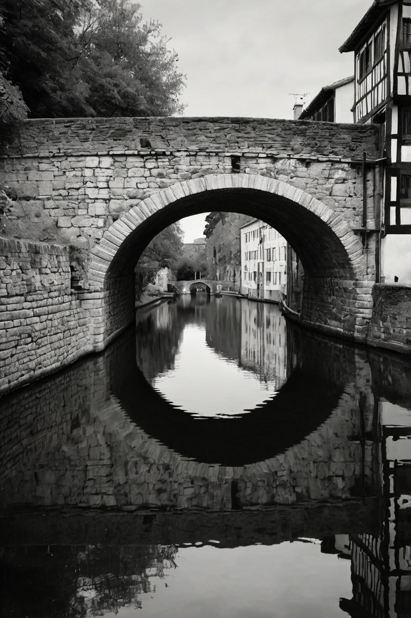 Old stone arch bridge over calm water with reflection (black & white)
