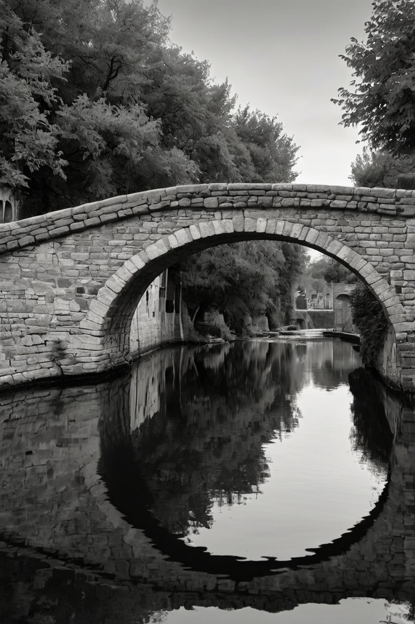 Old stone arch bridge over calm water with reflection (black & white)
